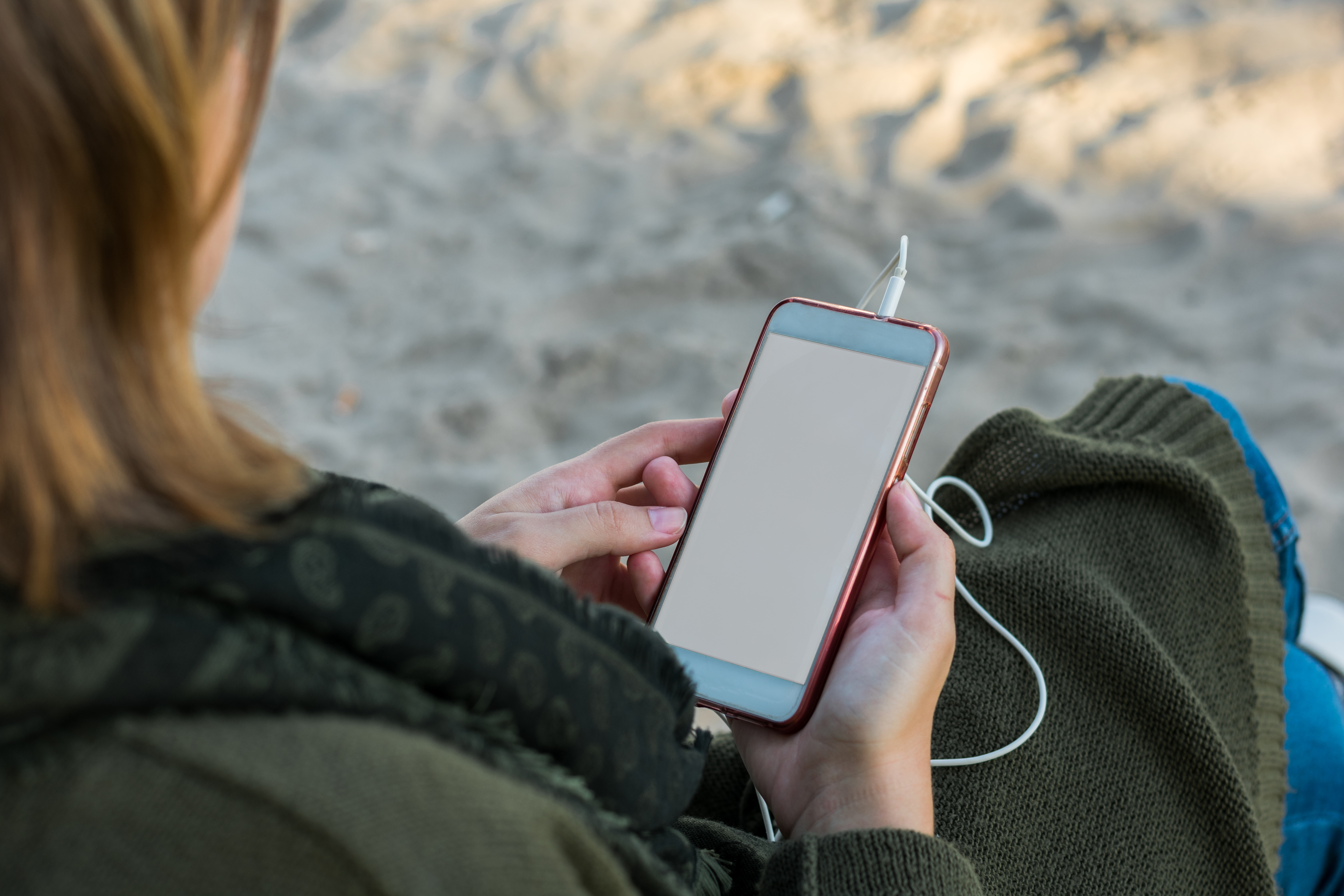 Stock photo of a mobile phone in the hands of a young woman in the beach. Technology.